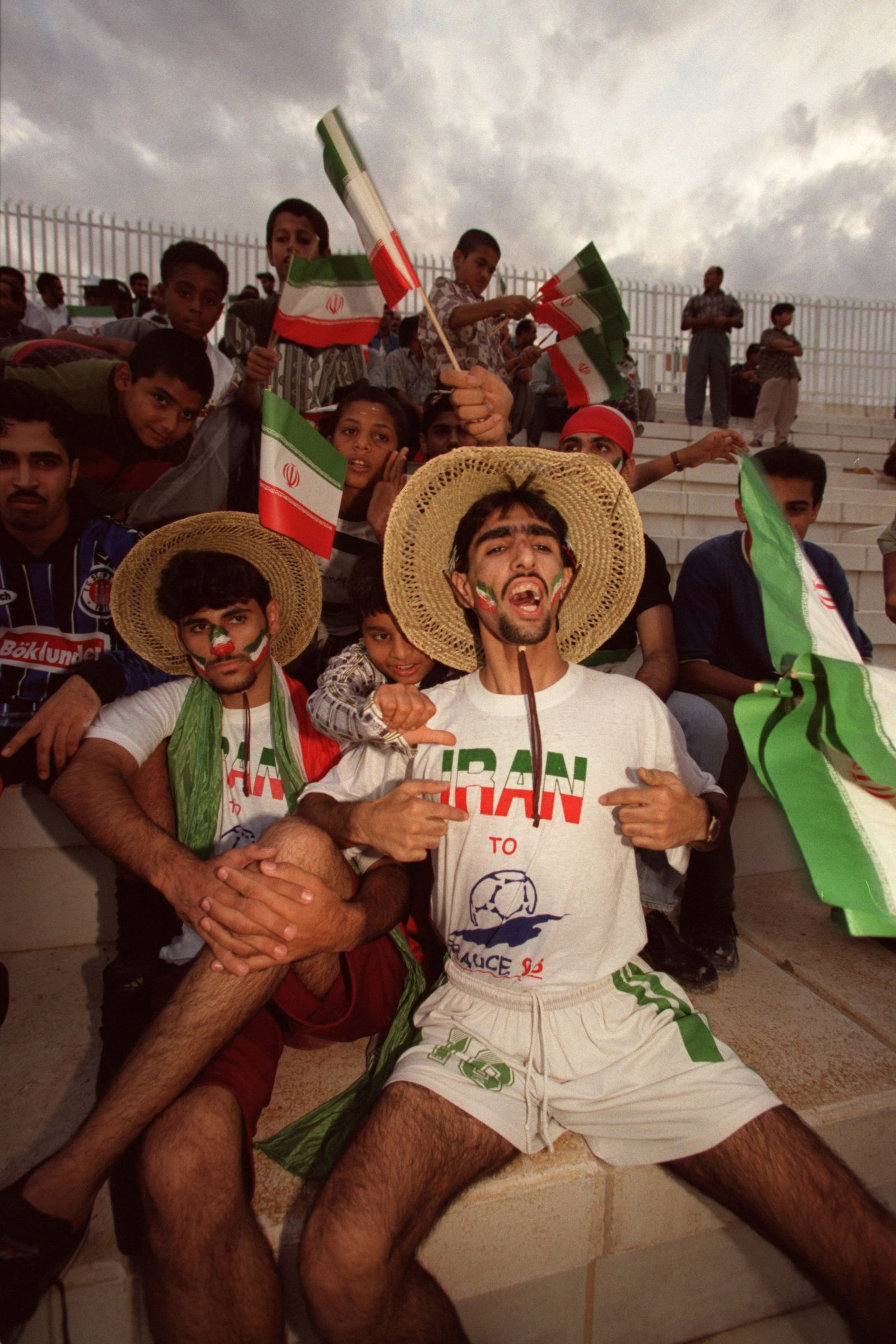 Image may contain Iran world cup history Face Head Person Photography Portrait Clothing Shorts Hat TShirt Adult Child...